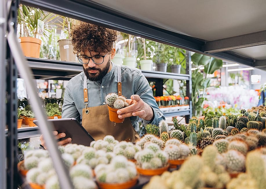 An owner checking potted cactus plants and its inventory with a digital tablet in the plant shop. — Anatoliy Cherkas // Shutterstock