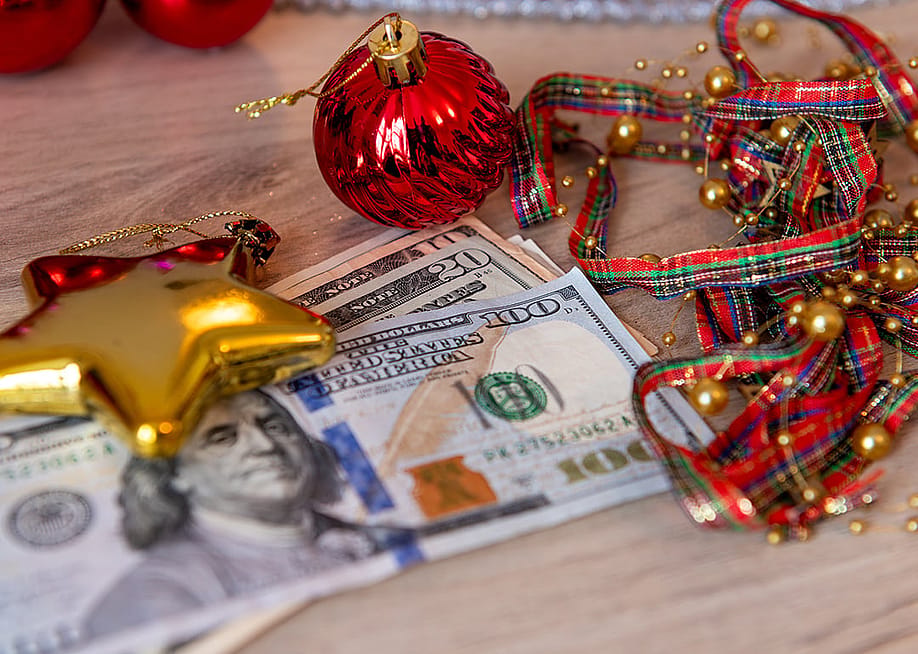US dollar bills and Christmas decorations on a desk. — Yau Ming Low // Shutterstock
