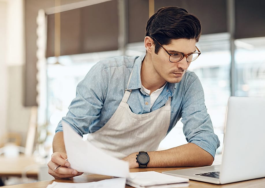 A restaurant owner carefully reviewing business documents. — PeopleImages // Shutterstock