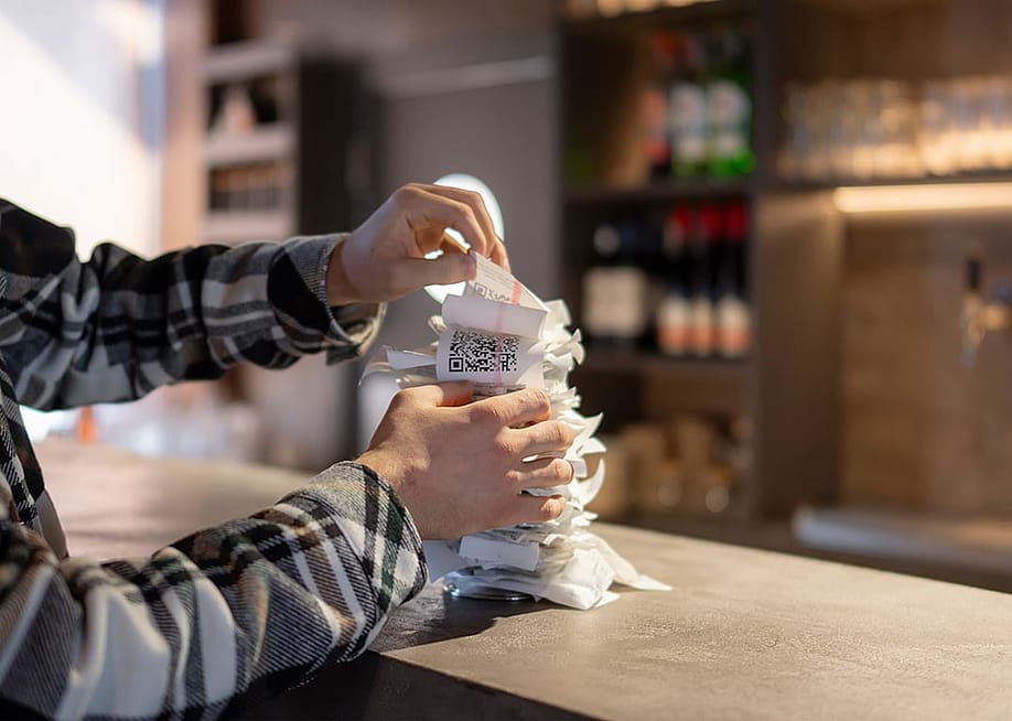 A waiter organizing a stack of order receipts after the lunchtime rush in the restaurant. — Mike_shots // Shutterstock