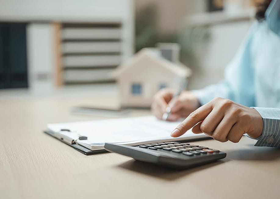 A property professional working on a document and using a calculator. — Garun .Prdt // Shutterstock