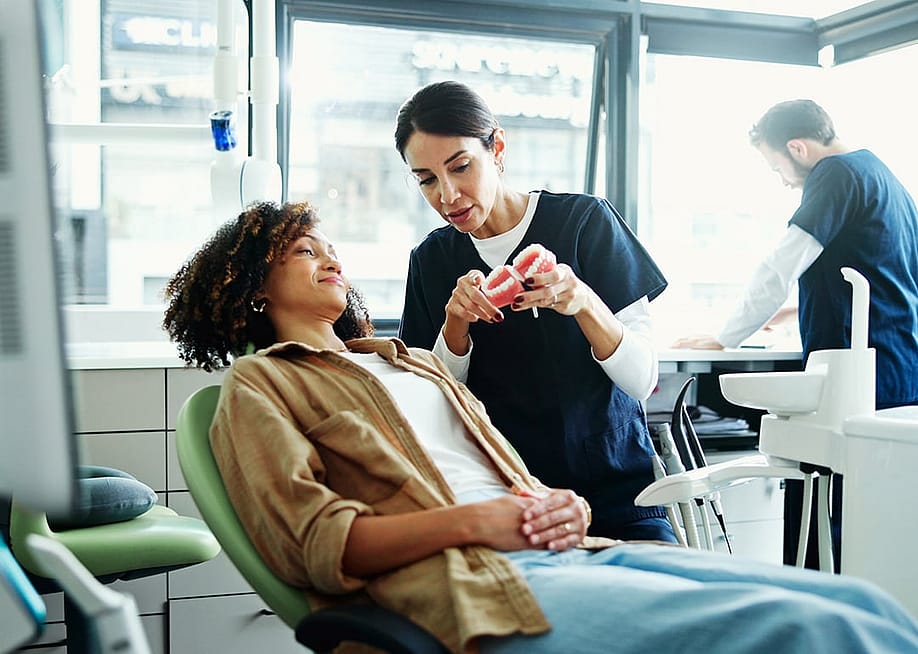 A female patient in a dental clinic being assisted by a dental staff in checking or choosing denture plans. — PeopleImages // Shutterstock