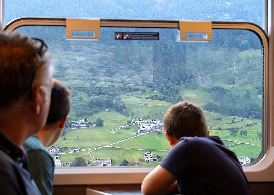 A family enjoying the scenic railway journey across Alpine villages in Switzerland. — Matteo_Barbera // Shutterstock