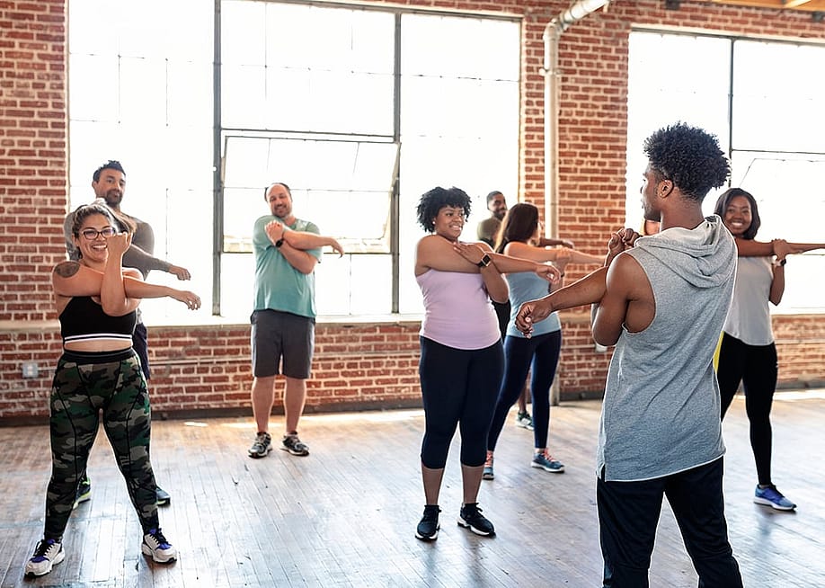 A dance trainer and his students stretching in a studio. — Rawpixel.com // Shutterstock
