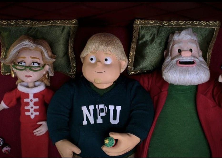 A boy on a bed in between Santa and Mrs. Claus.