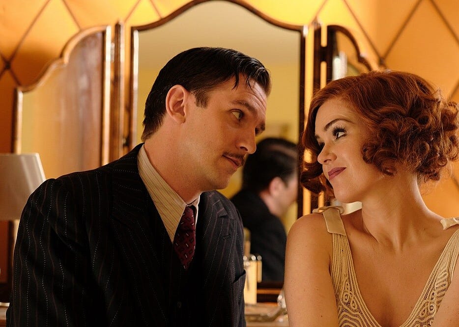 Isla Fisher and Dan Stevens looking longingly at one another.