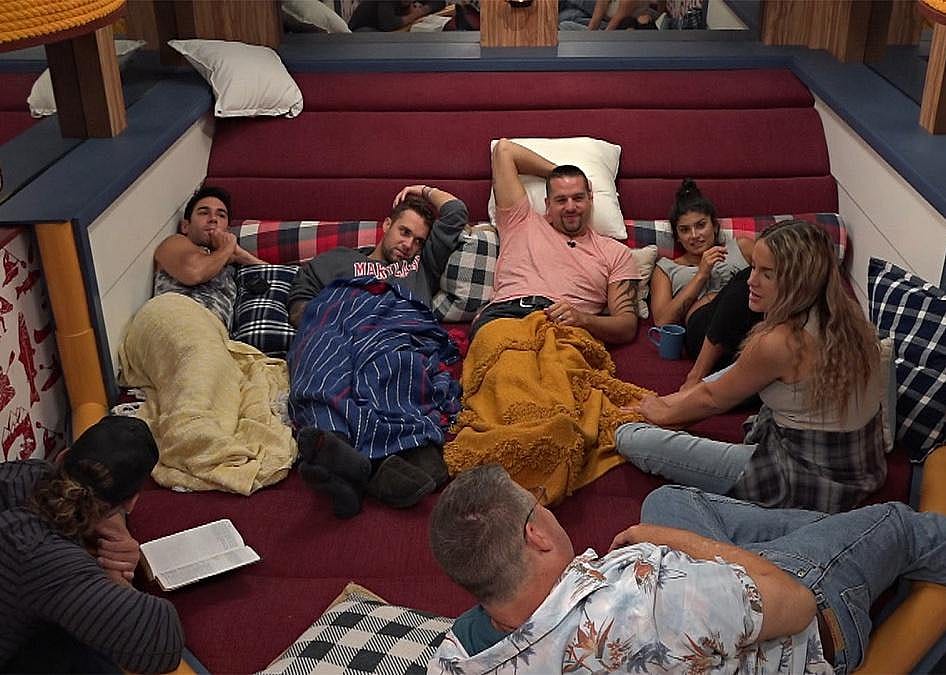 A circle of people lie on the floor talking.