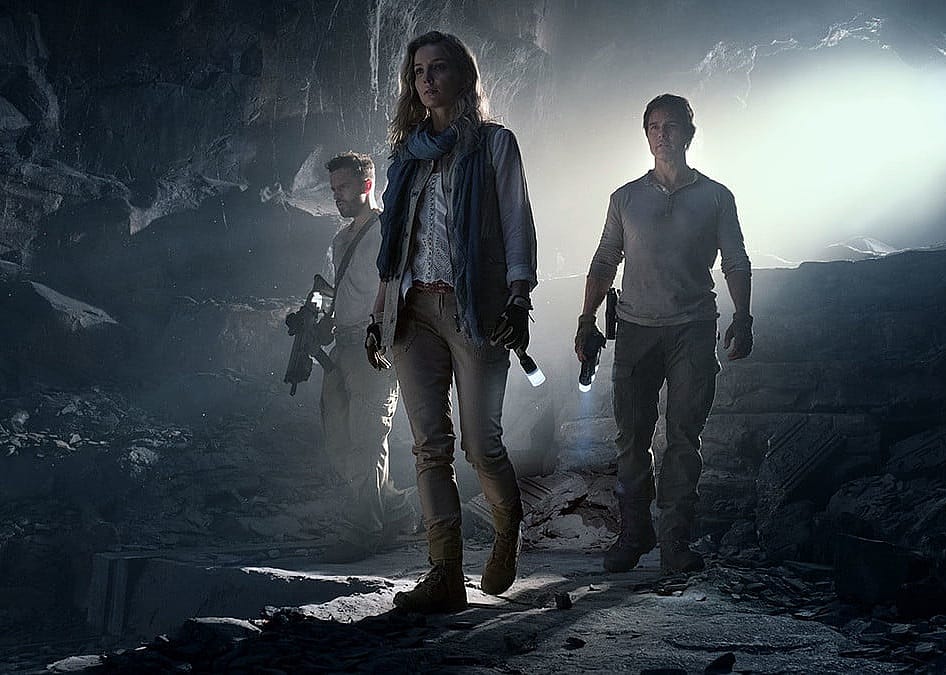 Three people in a dark cave with flashlights.